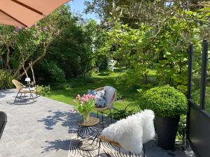 un chien blanc assis sur une chaise dans un jardin dans l'établissement Les Berges, à Bourbourg