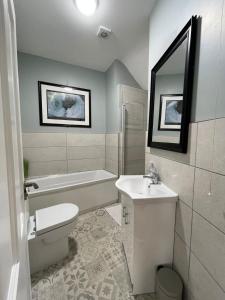 La salle de bains est pourvue de toilettes, d'un lavabo et d'une baignoire. dans l'établissement Tonn Ruray Sea View Luxury 2 Bed Apartment, à Dundrum