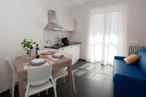 a kitchen and living room with a table and a blue couch at Brichett Deluxe Rooms in Alba