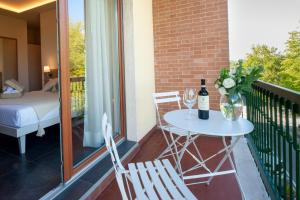 a balcony with a table with a bottle of wine and two chairs at Brichett Deluxe Rooms in Alba