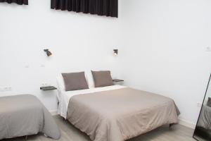 a white bedroom with two beds and a mirror at Nuevo Apartamento Sevilla centro, Trastamara 25 in Seville