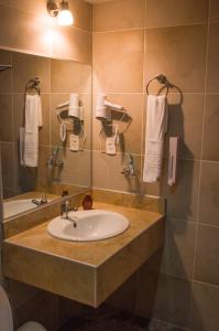 a bathroom with a sink and a mirror and towels at Hotel Mitru - Tarija in Tarija