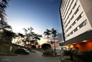 a building with a car parked in a parking lot at Transamerica Executive Belo Horizonte in Belo Horizonte