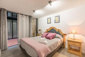 sypialnia z dużym łóżkiem z różowymi poduszkami w obiekcie The Bullring Suites w Sewilli