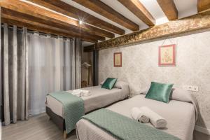 dwa łóżka w pokoju z drewnianym sufitem w obiekcie The Bullring Suites w Sewilli