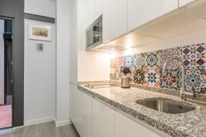 kuchnia ze zlewem i ścianą wyłożoną kafelkami w obiekcie The Bullring Suites w Sewilli