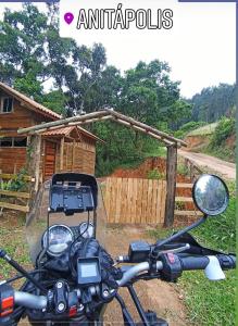 une moto garée devant une maison dans l'établissement Cabanas Pousada Esmeraldas, à Annitapolis