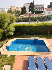 una pequeña piscina con sillas azules junto a ella en Apartamento Carihuela a 300 metros playa, en Torremolinos