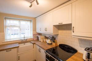 a kitchen with white cabinets and a stove top oven at Stay in Westow in Westow