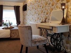 a bedroom with a desk and a chair with a mirror at Cobblers Cottage in Dalton in Furness