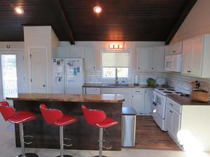une cuisine avec des armoires blanches et des tabourets de bar rouges dans l'établissement Summersalt, à Southern Shores