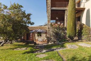 ein Haus mit einem Garten und einer Terrasse in der Unterkunft La masovería de Mas Redortra in Sant Pere de Torelló