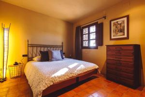 a bedroom with a bed and a dresser and a window at La masovería de Mas Redortra in Sant Pere de Torelló