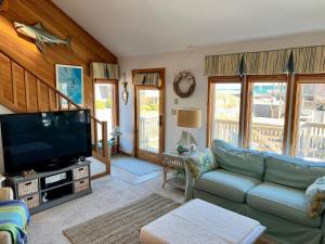 a living room with a couch and a flat screen tv at My Three Gulls in Kill Devil Hills