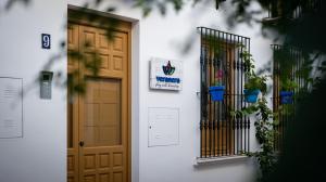 a white building with a door and two plants at Veranera Hostel in Estepona