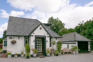 a white house with plants and flowers in pots at Luss Cottages at Glenview in Luss
