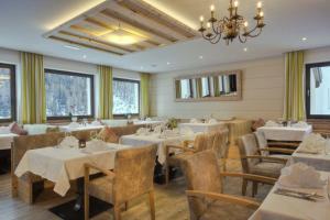 a restaurant with tables and chairs and a chandelier at Hotel Gampen in Solda