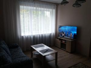 a living room with a couch and a flat screen tv at Sunrise in Rēzekne
