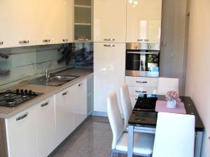 a kitchen with white cabinets and a sink and a table at Apartment Opatija Lavanda in Opatija