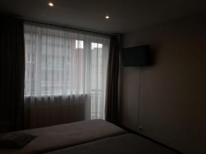 a bedroom with a window with a bed and a television at Sunbeam in Rēzekne