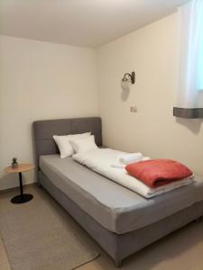 a bed in a room with a red blanket on it at Sakura Apartment in Mosonmagyaróvár