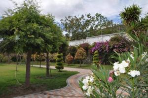 einen Garten mit Bäumen und Blumen und einem Gehweg in der Unterkunft Lujosa Quinta Vacacional Ibarra in Ibarra