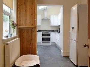 a kitchen with white cabinets and a white refrigerator at Cats Cottage in Kessingland