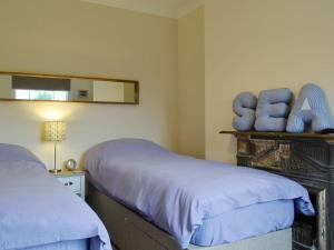Un dormitorio con 2 camas y un estante con un tarro. en Cats Cottage, en Kessingland