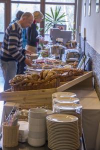 a man standing at a buffet with plates and food at Horský Hotel Javor in Dolní Malá Úpa