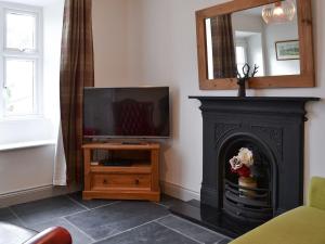a living room with a fireplace and a television at Coniston Cottage in Coniston