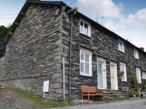 a stone building with a bench in front of it at Coniston Cottage in Coniston