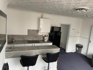 eine Küche mit einer Theke und ein paar Stühlen darin in der Unterkunft Apartments Azalea Terrace in Sunderland