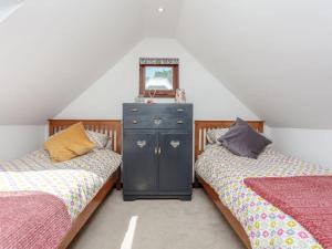 a attic bedroom with two beds and a dresser at The Barn in Coldwaltham