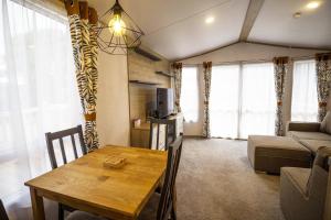 a living room with a table and a couch at Beautiful Caravan With Decking At Azure Seas In Suffolk, Sleeps 6 Ref 32004az in Lowestoft