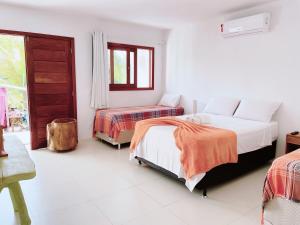 a white room with two beds and a window at Pousada dos Poetas in Barra Grande