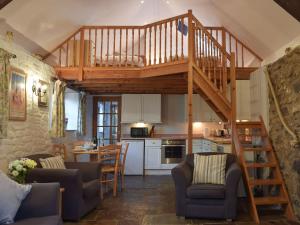 a living room with a wooden staircase in a house at Beats Cottage in Llangwm