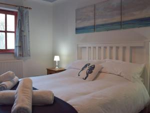 - une chambre avec un grand lit blanc et des oreillers dans l'établissement Beats Cottage, à Llangwm