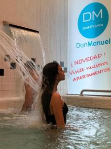 Una donna in piedi nell'acqua con una fontana di Gran Hotel Don Manuel a Cáceres