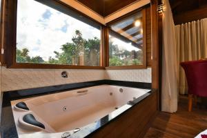 bañera grande en una habitación con ventana en Stillo Gramado Dutra, en Gramado