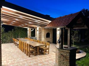 a patio with a wooden table and chairs under a pavilion at Holiday home Casa Rio in Vinkovci