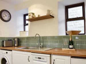 a kitchen with a sink and a clock on the wall at Rose Cottage in Lofthouse
