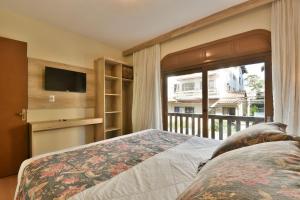 um quarto com uma cama, uma televisão e uma varanda em Stillo Gramado Aconchego em Gramado