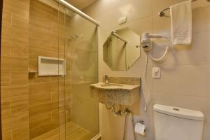 uma casa de banho com um chuveiro, um WC e um lavatório. em Stillo Gramado Aconchego em Gramado
