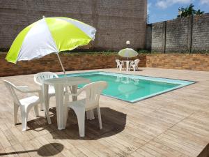 - une table et des chaises avec un parasol à côté de la piscine dans l'établissement Hotel Legal, à Capanema