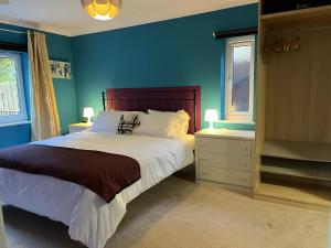 a blue bedroom with a bed and two windows at Beautiful 2 Bed Apt with Hot Tub in Blaydon Burn in Blaydon
