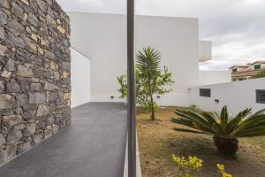 a stone wall and a walkway next to a building at Secret Beach House in Água de Alto