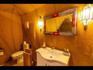a bathroom with a sink and a toilet and a mirror at Merzouga Luxury Camp in Tisserdmine