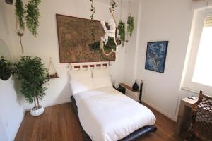 a bedroom with a bed with white sheets and plants at Il Chiostro in Cagliari
