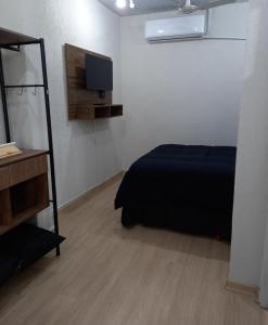 Schlafzimmer mit einem Bett und einem Flachbild-TV in der Unterkunft FLAT LOCAÇÃO TEMPORADA NO CENTRO DE ITAPIRA in Itapira
