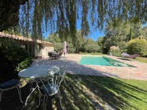 een patio met een tafel en stoelen naast een zwembad bij FUVOLEA, Maison de vacances à 15 min du centre d'Aix-en-Provence, piscine chauffée en saison - jardin - parking privé gratuit in Fuveau